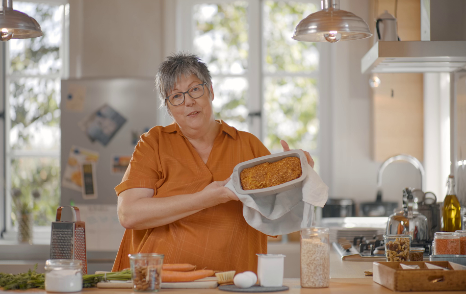 Eine glückliche, ältere Frau mit Diabetes gestaltet ihre Ernährung gesund mit dem Haferflocken-Brot.