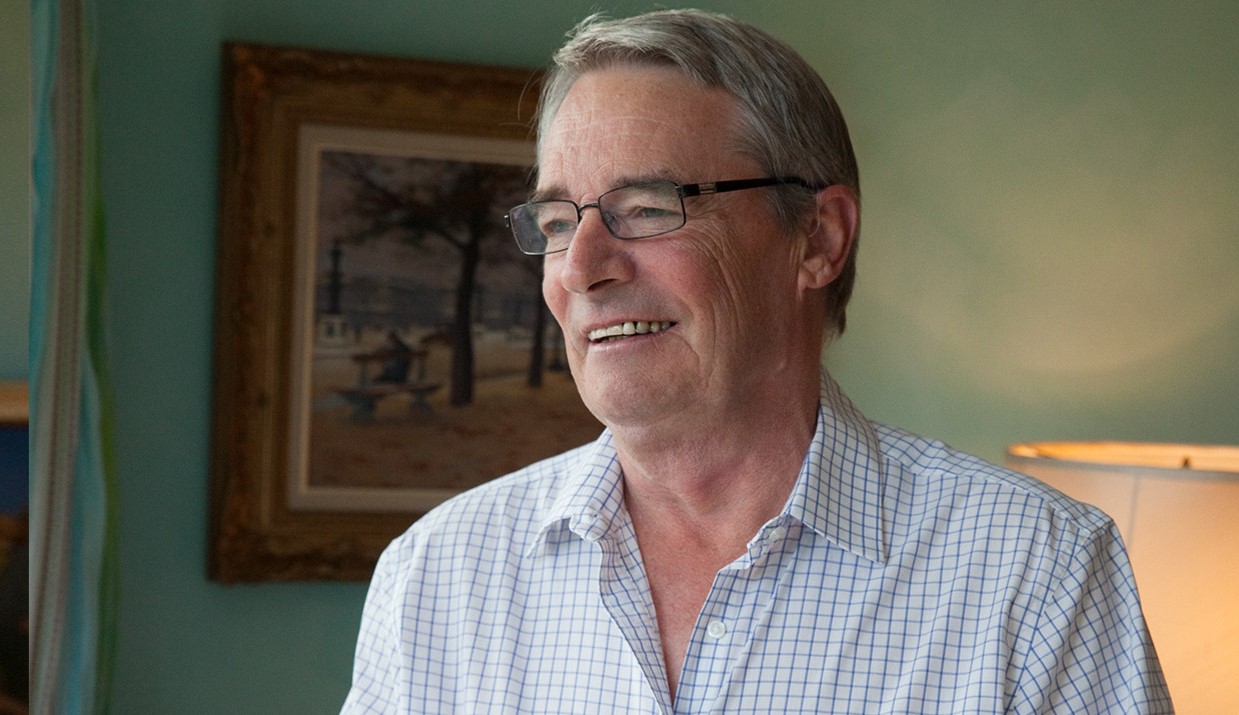 Mies istuu pöydässä kahvimuki kädessään.