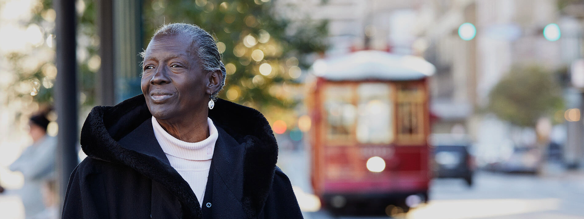 Woman standing on a street with an old tram in the background.