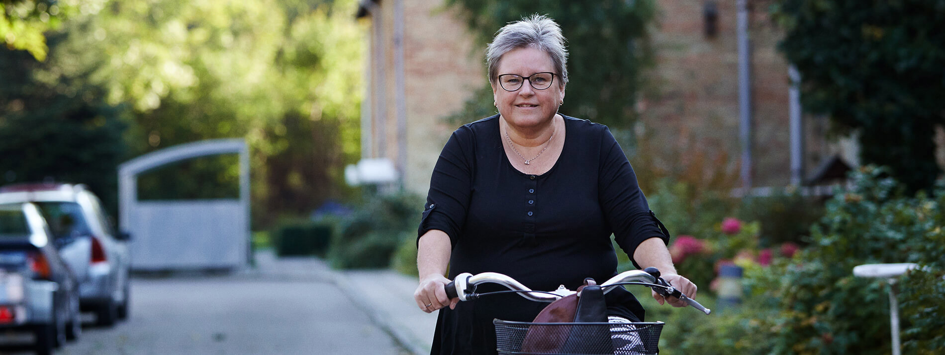 Woman biking in a street with flowers in the background.