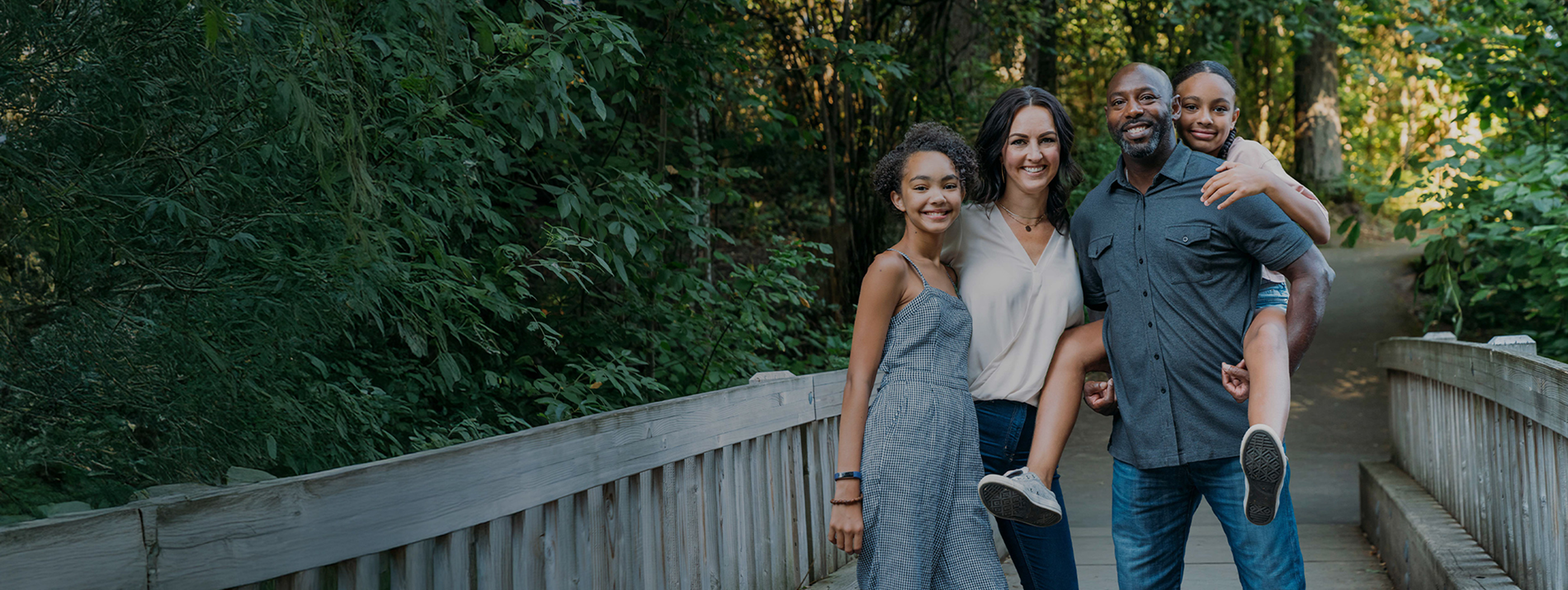 Family walking together outdoors on a sunny day, smiling and spending time in nature.