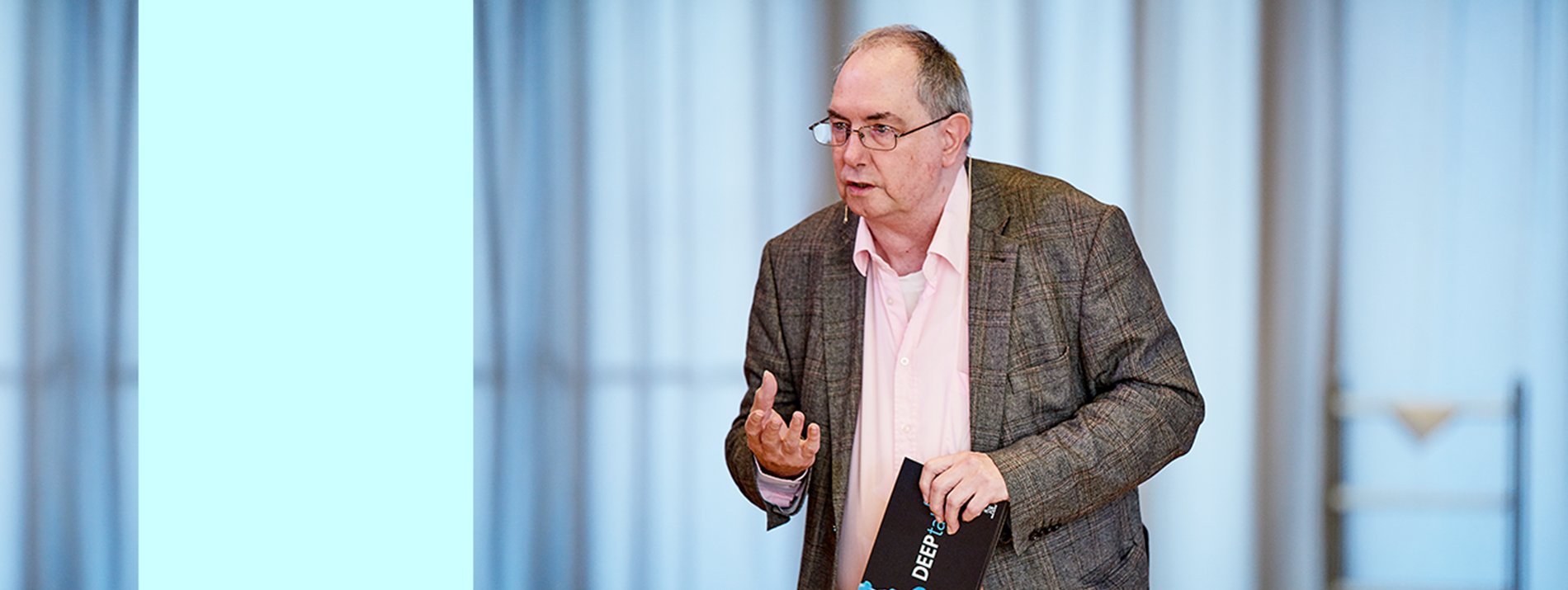 A man standing at a stage in the middle of a talk during a presentation.