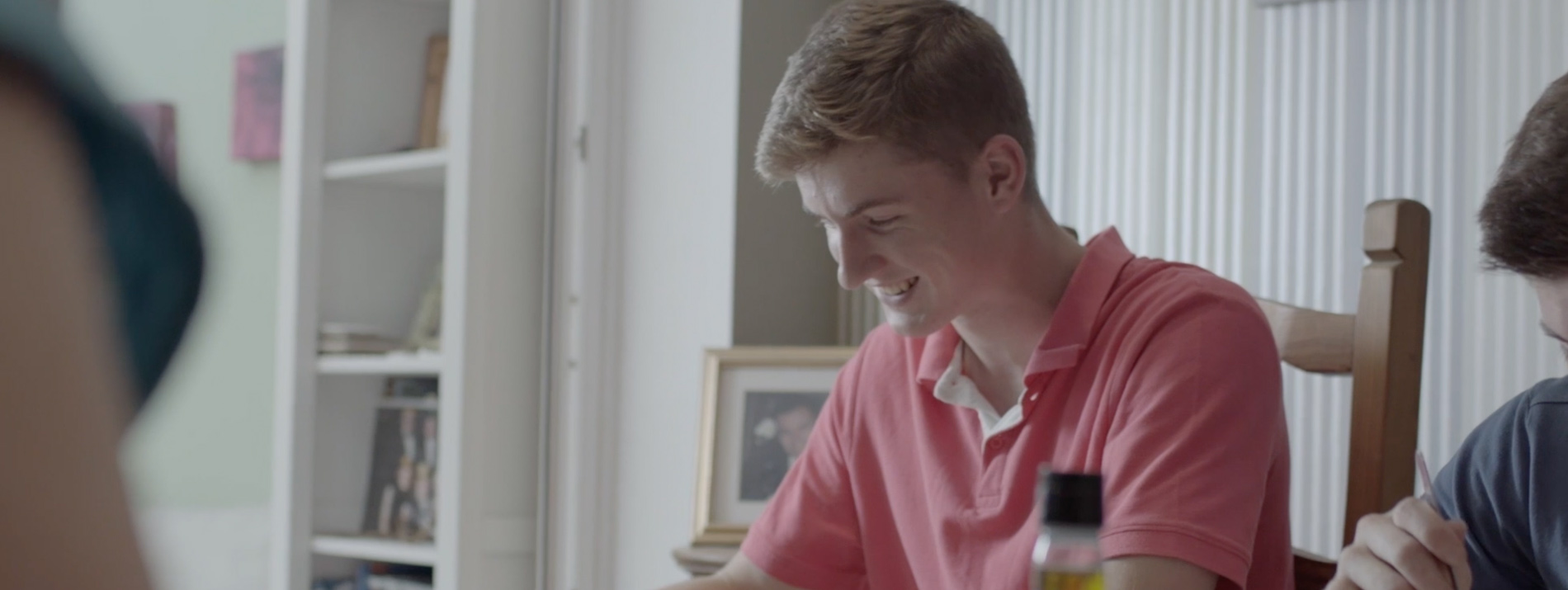 Young man sitting at a table smiling.