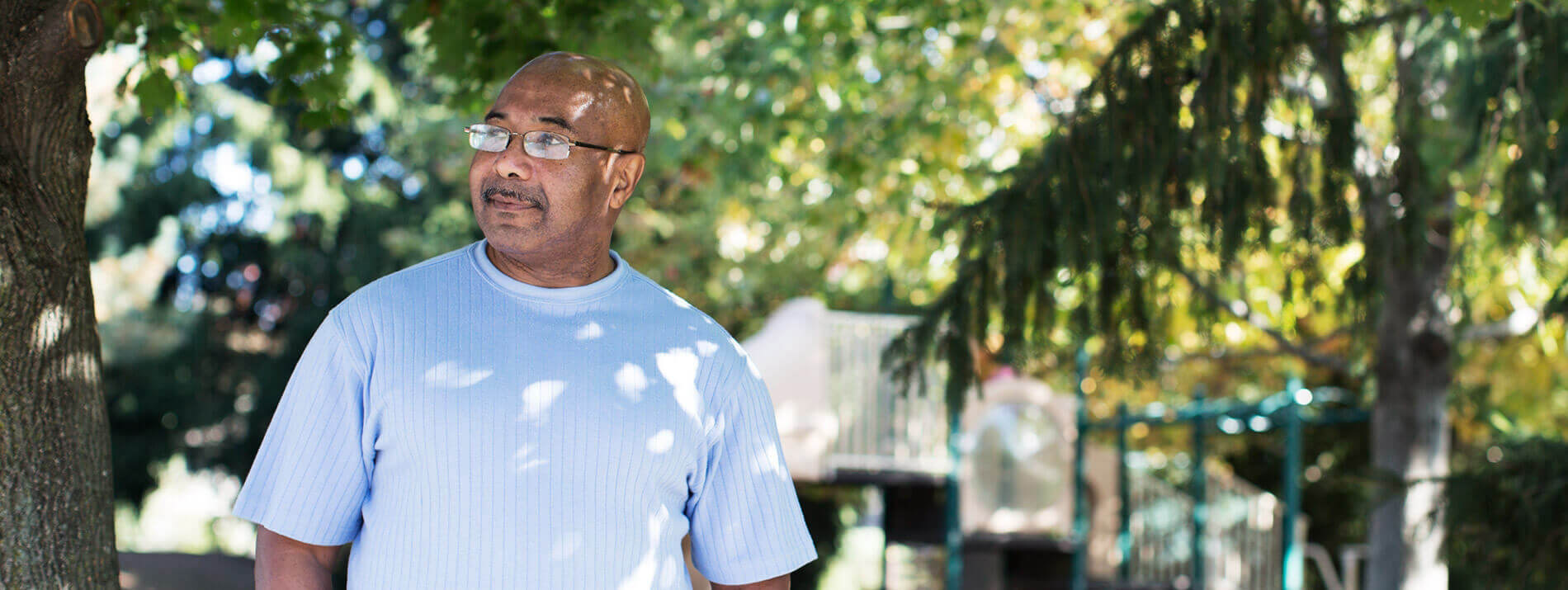 Man standing in the shade of trees.