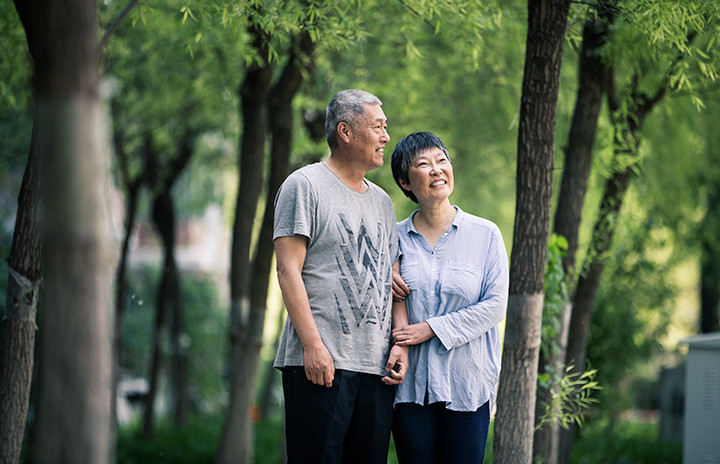 A man and a woman standing inbetween trees.