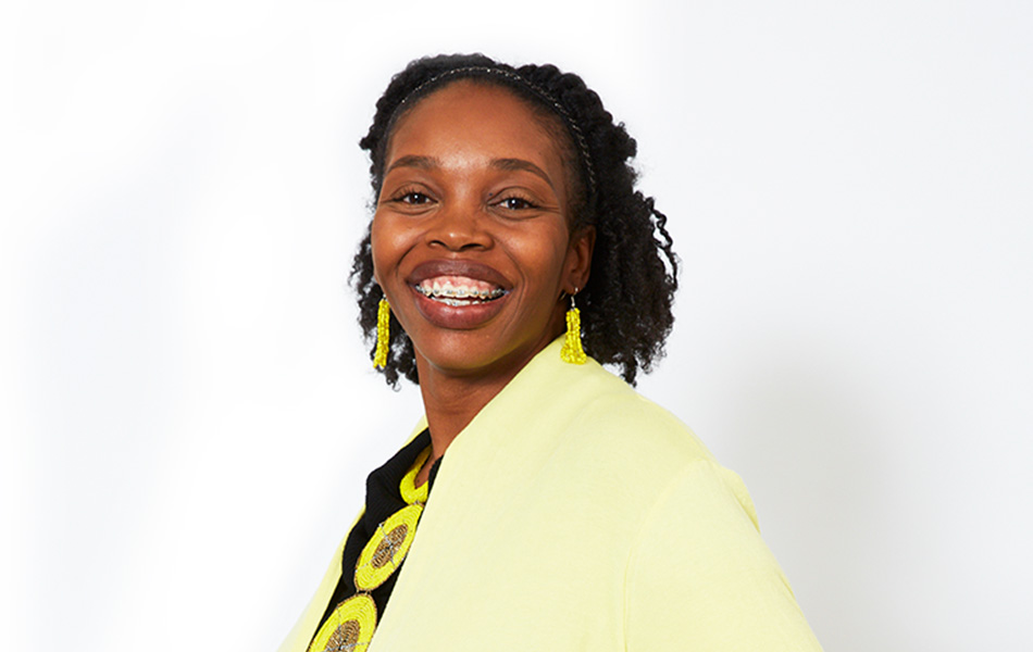 A centered portrait of a smiling woman wearing a yellow jacket.